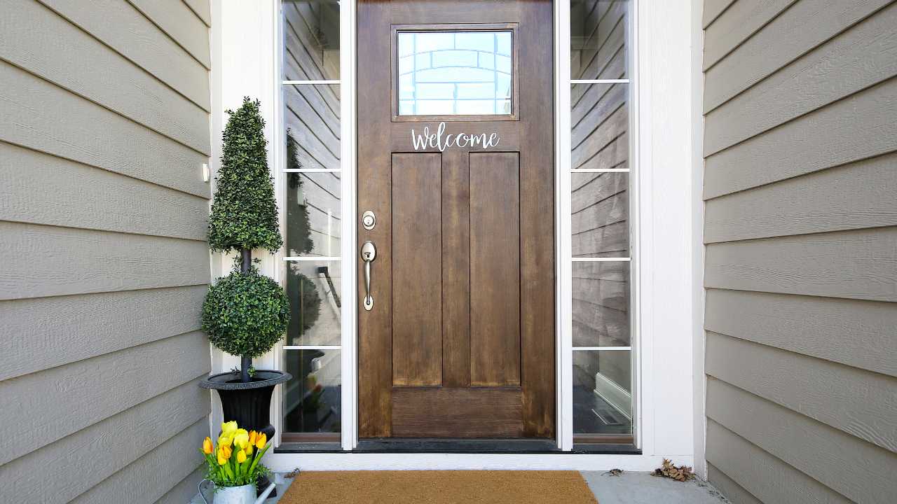Dark Wooded Door Leading to House with Welcome Sign on Front