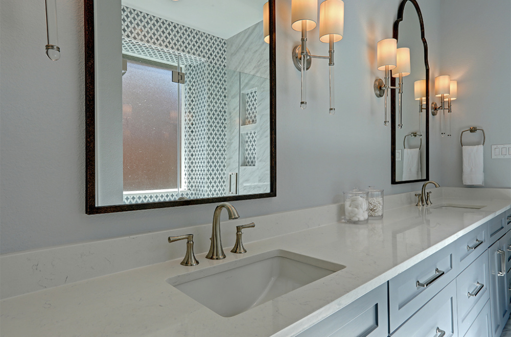 Modern bathroom with a double sink vanity, two mirrors, wall-mounted light fixtures, and a glass-enclosed shower in the background.