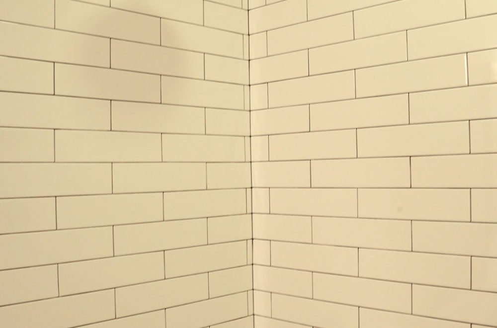 White rectangular subway tiles arranged in a staggered pattern form a corner wall.